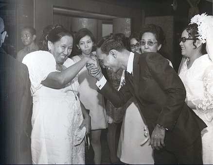 A son taking the hand of his mom and putting it to his forehead to show respect. This is an example of the Filipino tradition of mano po.