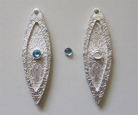 Silver marquise earring drops embedded with commercial fine silver bezel cups before firing, to be set with calibrated natural blue topaz cabochons after firing.