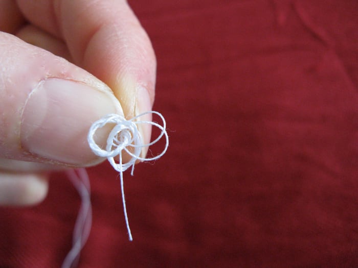 Run your fingers along the thread until the tangle catches on itself and becomes a tighter wad at the end of the thread.