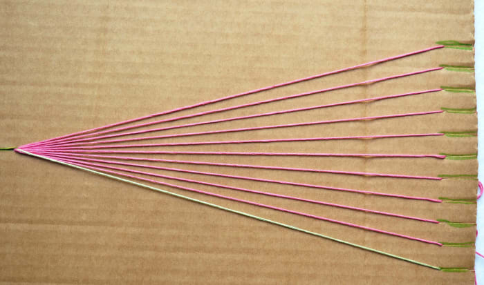 Separate the strings and pull each one down into its own slit. Make sure to put the background colored string into the slit all the way to the left as shown.