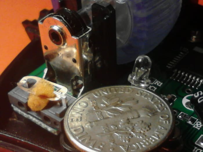 The small switch is on the left with a piece of orange memory foam already placed inside the switch. The dime is for size comparison. If you cannot work on something this small then get help or stop working on this until you are comfortable doing so.