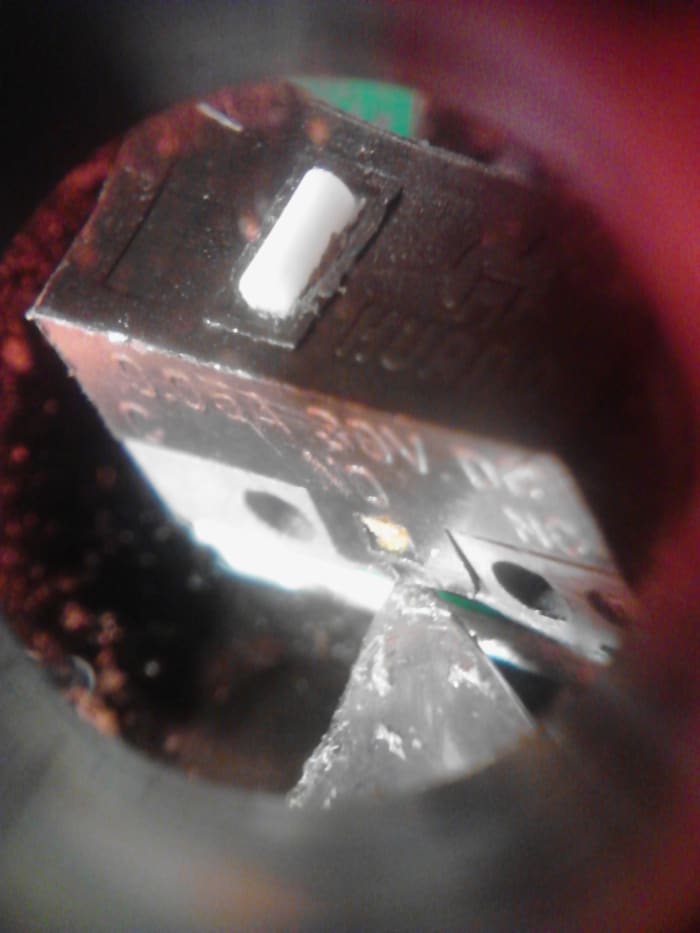 Close up shot of the latching point of this specific kind of switch. This switch has another identical tab on the opposite side of it that will come off once we remove the first side.