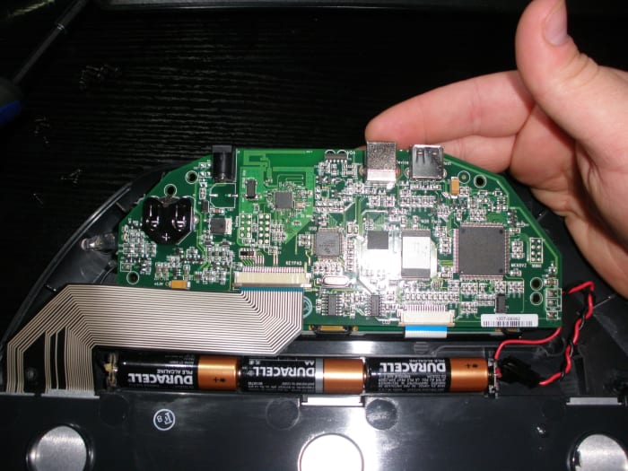 Gently lift the motherboard without putting any tension on the ribbon cables that are attached to it, and then remove the battery from its holder. Insert the new one positive or '+' side up and put everything back together.