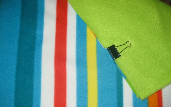 After choosing two types of fleece and cutting them into equal pieces, clip two layers together with a paper clip.