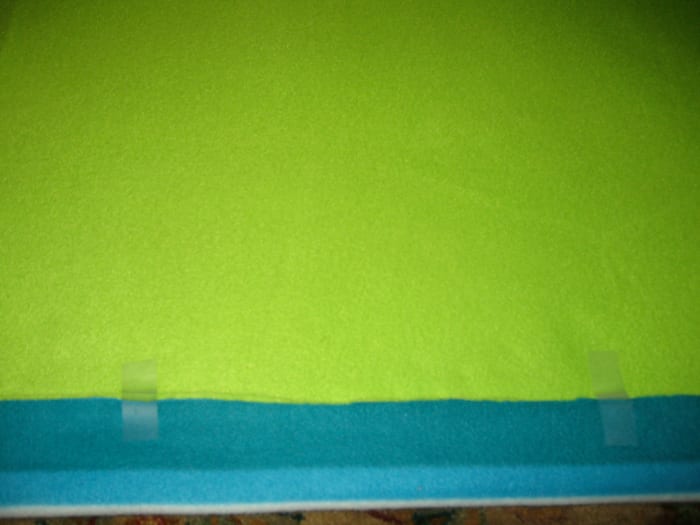 Fold the fabrics up about an inch and a half and tape along one side. Cut until you reach the top (solid green).