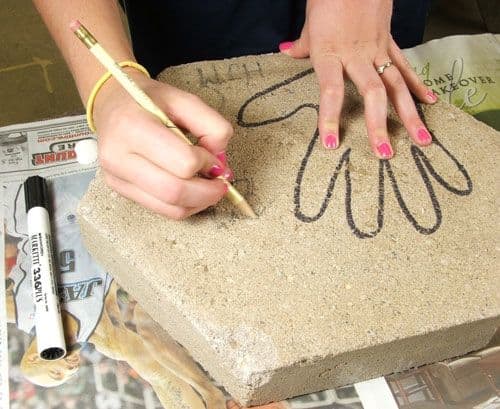 Step 1. Using a 2nd stone or a paper template pre-design your project using a marker to outline your hand imprint and any lettering you might want to include such as a date, artist initials, etc. Place your stained glass cobbles, seashells and/or any