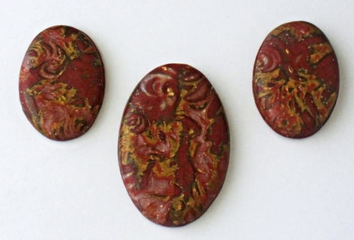 A selection of coordinating polymer clay mokume gane cabochons made from the same stack or billet