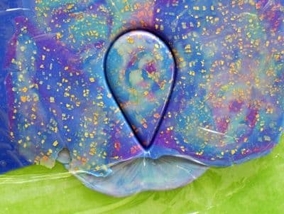 Cutter impression through plastic and polymer clay. See how cutting through the plastic wrap rounds the edges of the cabochon cutout?