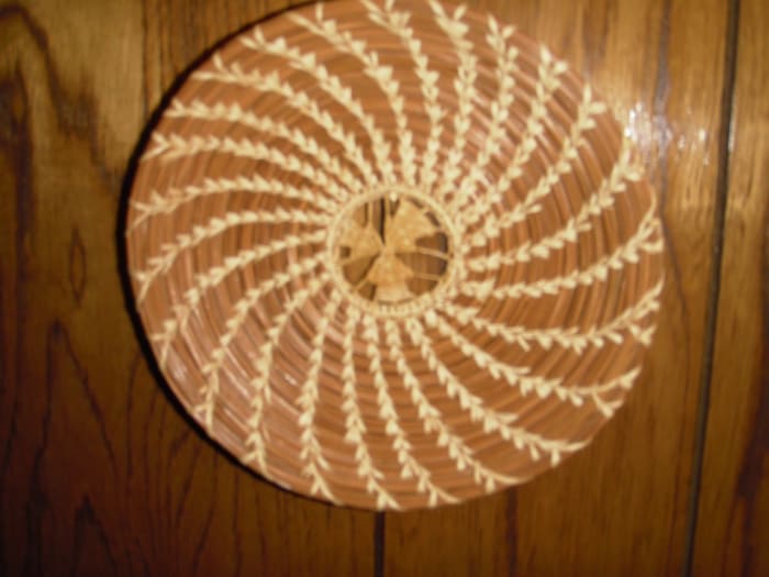 This decorative plate by J. Simpson has a slice of black walnut shell sewn into the starting coil.