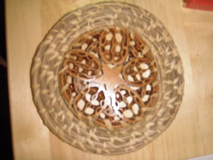 This decorative plate by J. Simpson has a wooden star surrounded by slices of walnut shell in the centre.
