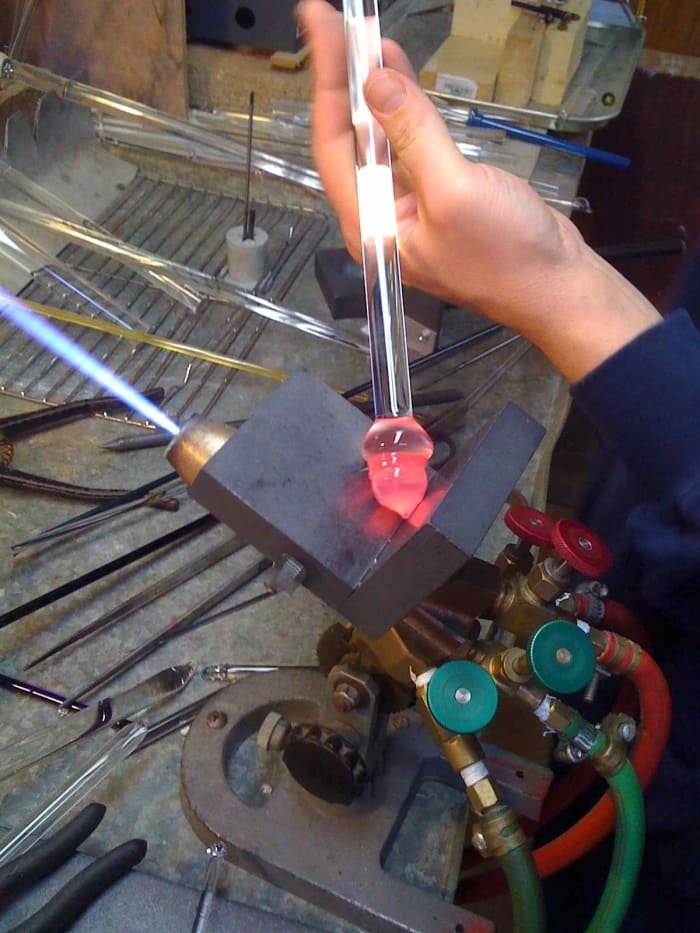 The Dichroic core is attached to the new rod and broken off of the original one. The core is being shaped prior to having more glass built up around it.