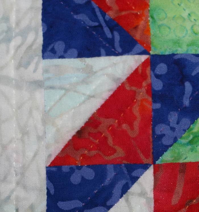 This quilt was spot cleaned and the red fabric ran when it got wet. Look at the white fabric along the diagonal seam to see where the fabric bled.