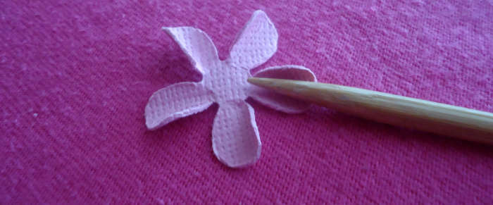 Now take another punched flower and use the skewer to curl the petal inward on one side. Repeat with each petal.