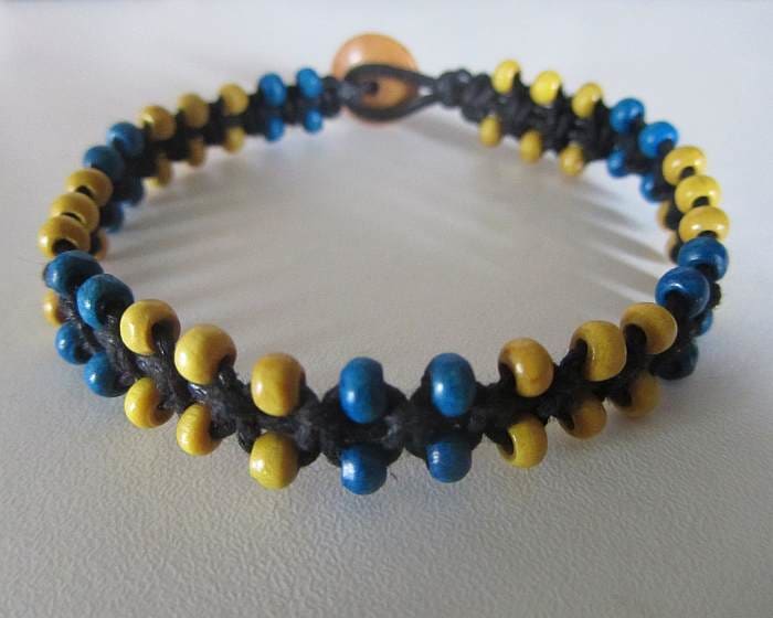 Macramé jewellery can be made using no metal components at all. This particular design using cotton cord and wooden beads. A clasp is created using a cord loop and a button.