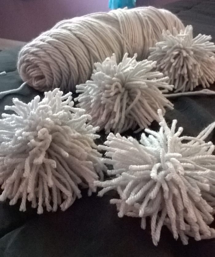 Four finished pom poms. Before we can use the pom poms to make a rug, we need to make them!