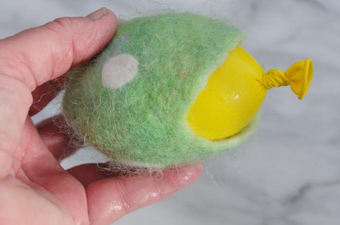 With the ball still inside, hit it against a table edge or against the sides of the sink until it shrinks back as shown here.