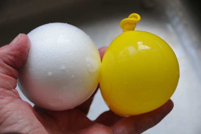 Inflating the balloon with a little water and air to approximately the same size as the small size polystyrene ball.
