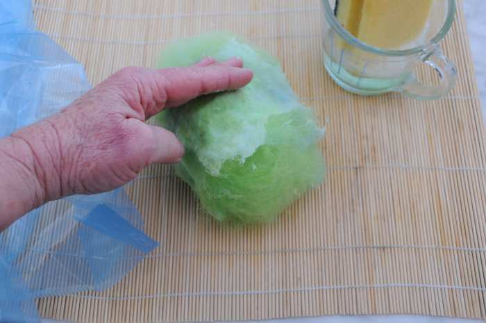 Dampen down the fibers gently with hot soapy water and then press them flat against the ball.