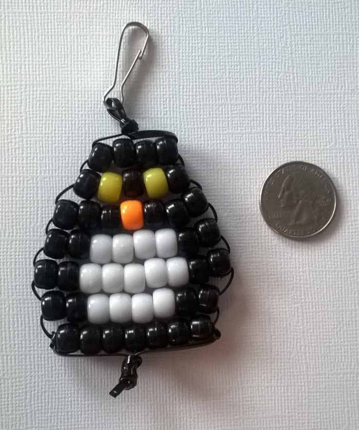 You could make any animal shape—like a penguin, for example! This beaded penguin key chain is placed next to a U.S. quarter to show size.