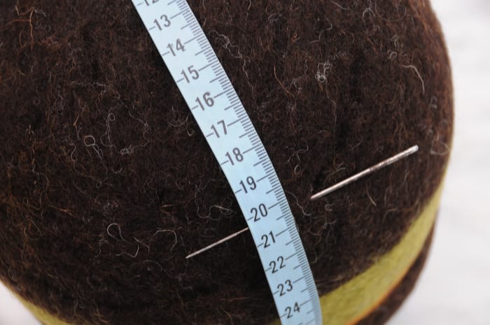 Marking the cutting line with a tape measure, felting needle indicates the start line
