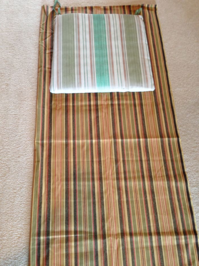 The old cushion is laying on top of the new fabric, which is folded in half lengthwise. I had not ironed the fabric yet--I ended up doing that after I had cut my pieces so it would be easier to work with.