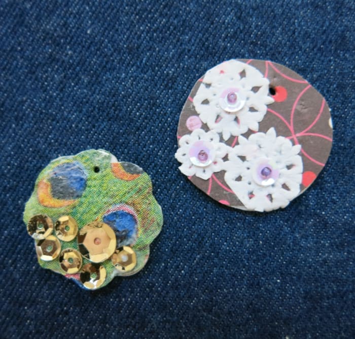 Use wrapping paper, stickers, postage stamps, paper doilies, buttons, and sequin to decorate your charms