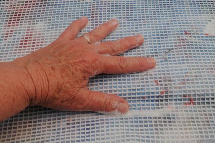 Cover with netting. Wet with warm soapy water. Smooth out the fibers and then turn the template over. Repeat on the other side with another layer of fine fibers.