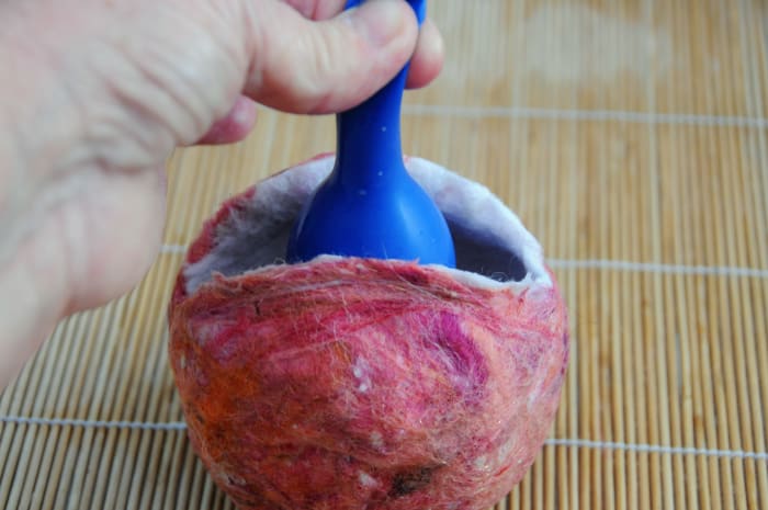 Insert the water filled balloon into the cavity of the purse and then inflate with a little air.