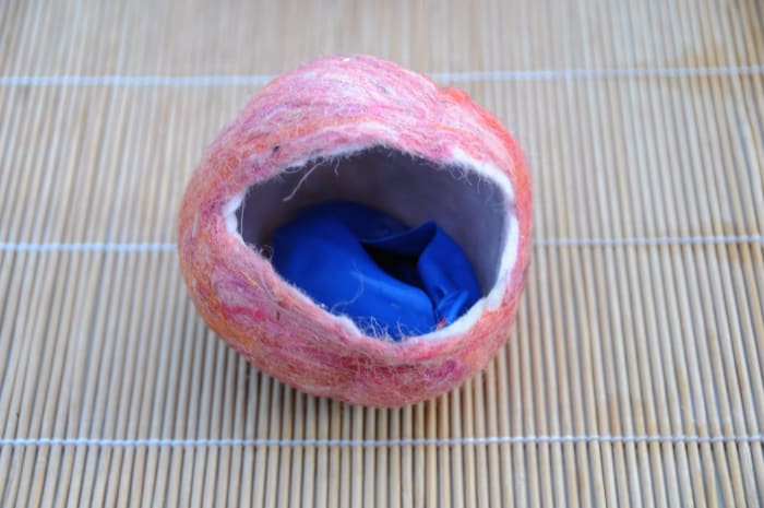 Prick the water filled balloon and remove it from the cavity of the coin purse in the making.