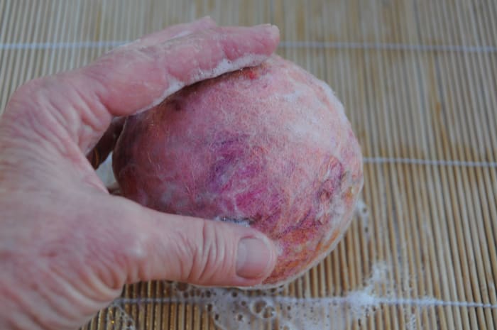 Smooth out the fibers on the surface of the ball by rolling them on the bamboo blind.