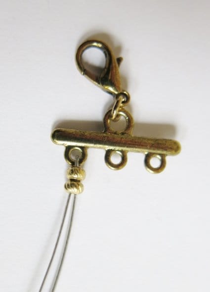 Feeding your beading wire through your crimp beads to attach the clasp to your necklace.