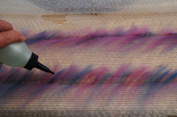Cover the wool roving with a fine layer of wool roving and wet as shown with tepid soapy water.