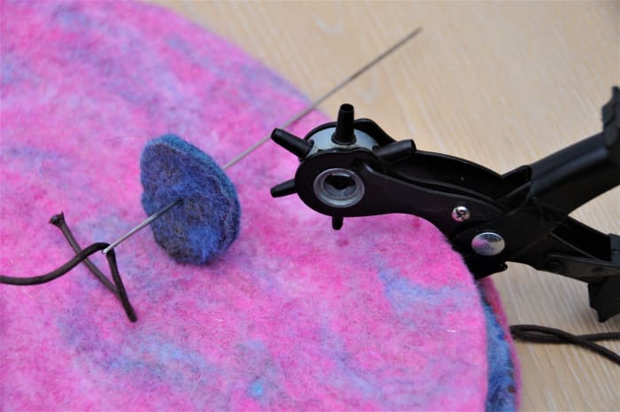 Cut 1 tiny hole in the center of the 2 felt pieces using a leather punch or tiny scissors. Placement can be sourced using a large eyed doll needle.