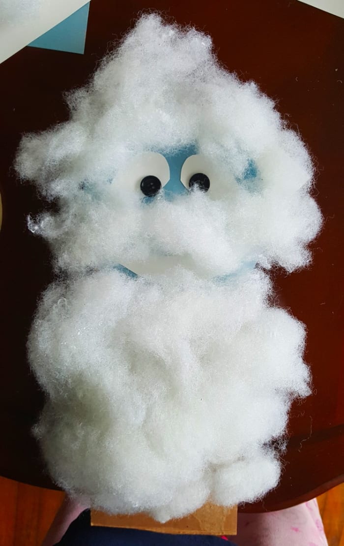 Glue the head onto the cardboard. Glue sections of pillow stuffing above the eyes to make Bumble's hair.