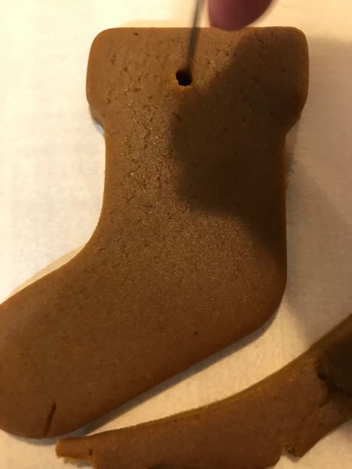 Use a toothpick or small skewer to make a small hole in the top of the cookie ornament for hanging. Do it before baking or you'll never get it right without breaking the cookie. The cookies puff just a touch, but not much, so the hole stays in place.