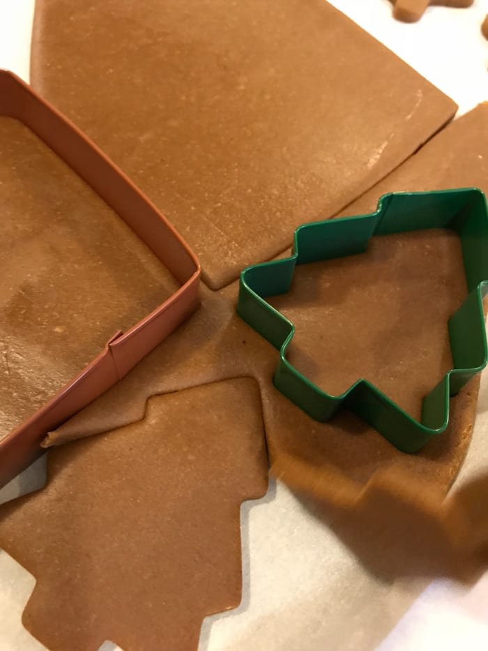 The easiest way to cut clean shapes is to cut on the parchment, then remove the dough from around the shapes. The extra dough can be rerolled. Keeping the cookies right on the parchment means you can move them to the baking sheet without distortion.