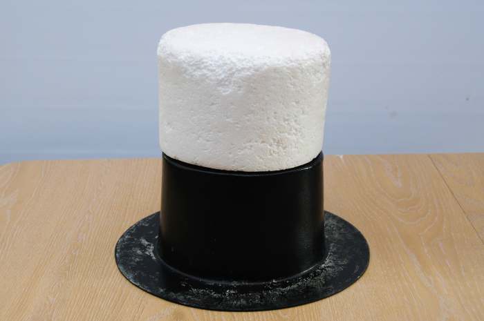 The polystyrene hat block balanced on the hat shaper. This was used inside the waste-paper bin sleeve to increase the height of the hat.