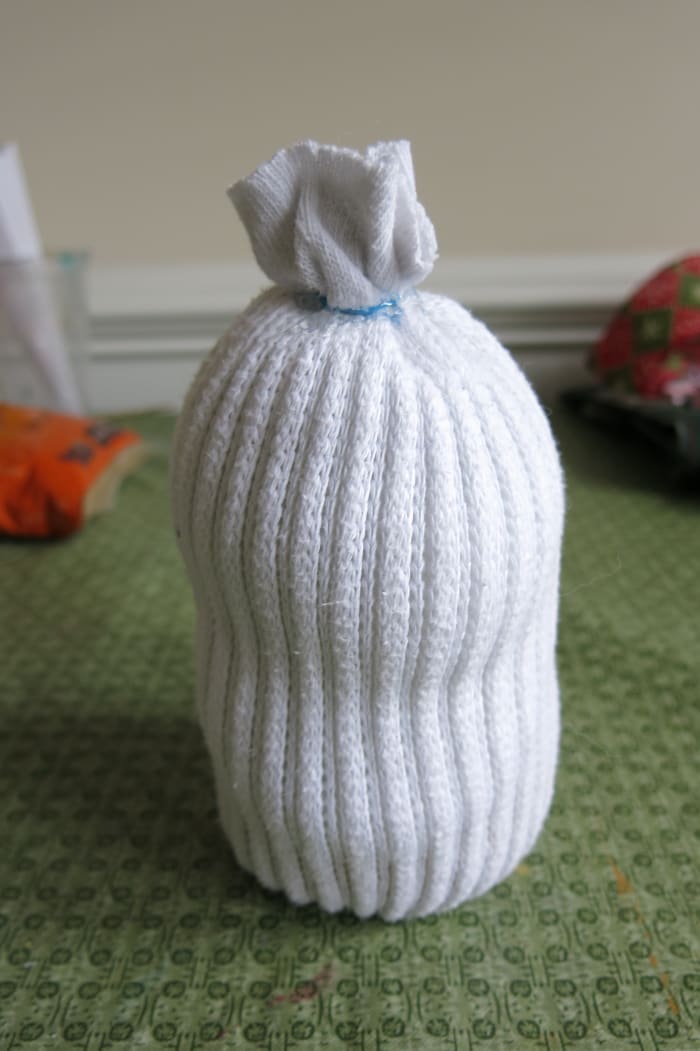 Fill the body of your sock snowman with fiber fill or cotton balls before closing it off with a rubber band or thread.