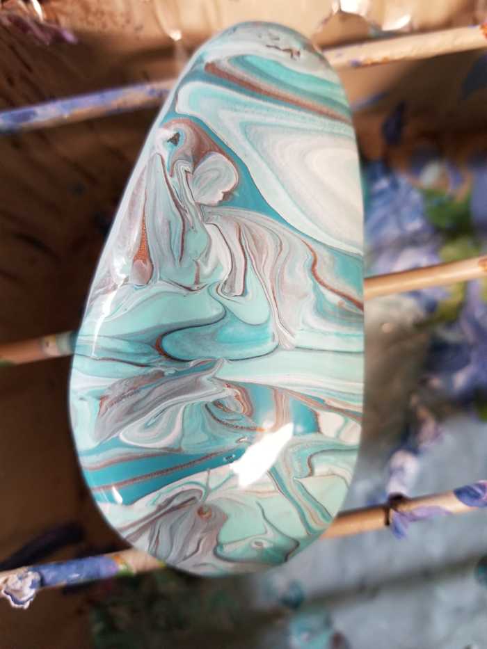 To spread the paint, gently tilt the rock in different directions but don't go overboard.