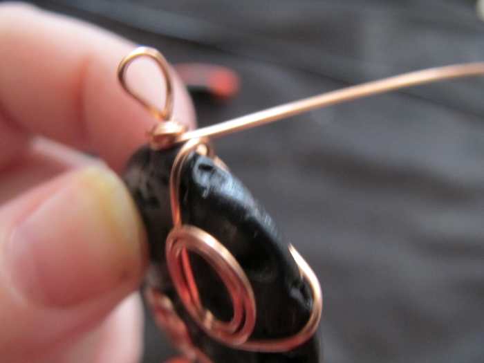 Once again, criss cross the wire around the back of the stone; this time, wrap it tightly around the coil on the necklace bail.