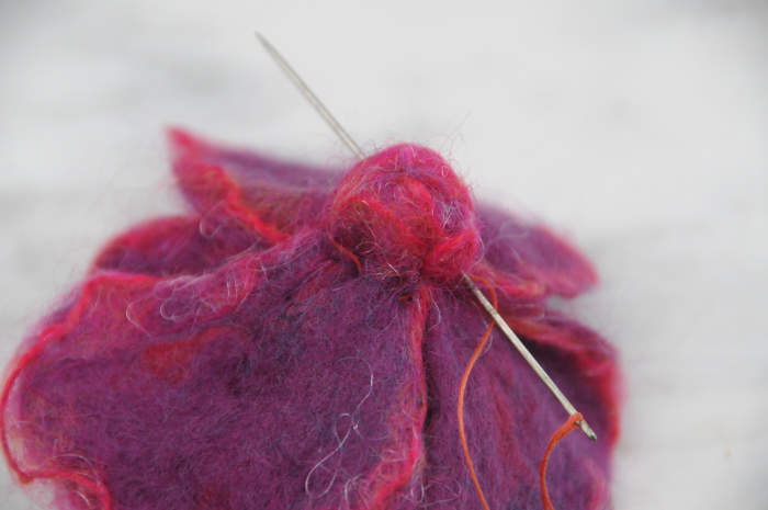 Sew right though the back of the flower from several points as shown and remove elastic band.