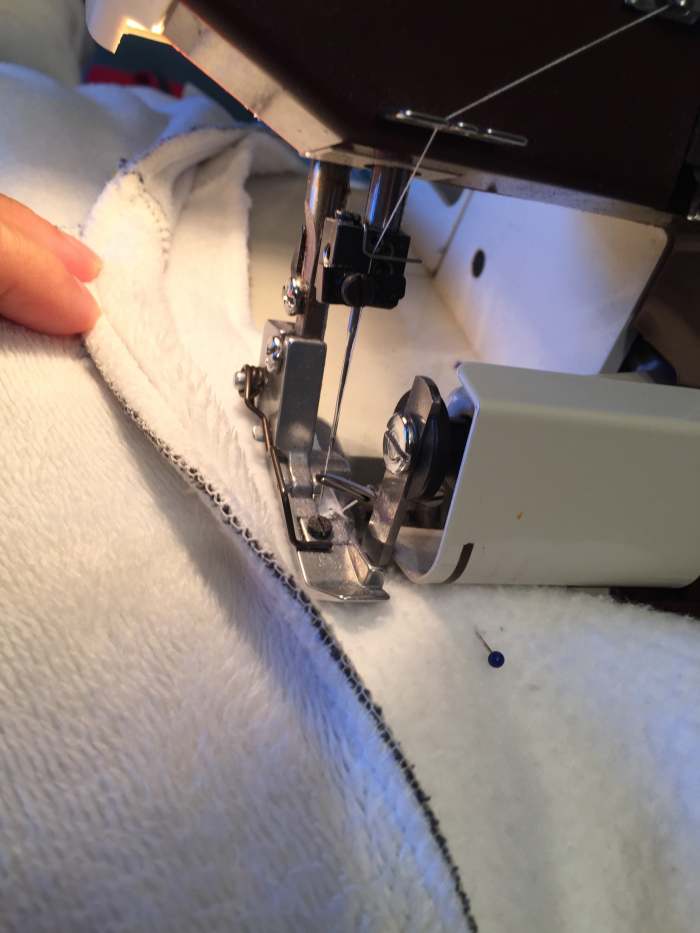 Here I am following the edge of the guide shirt. The serger blade will cut away the excess while also nicely finishing the edge. Be aware of your pins! The blade does not forgive!