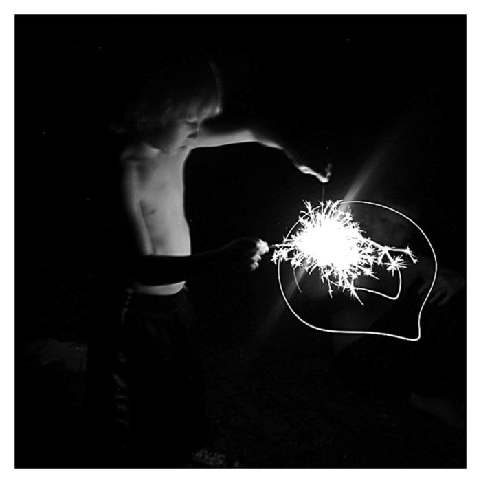 FIRECRACKER When I took this photograph, I knew my light settings were off and that the lighting was impossible. I kept shooting and later discovered this image. The light opposed to the fading body can be symbolic of childhood and the bright future.