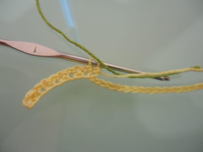 Have the new color ready to pull through the final stitch of the previous color. Place the old color on the wrong side of the work so it will not show in the end.