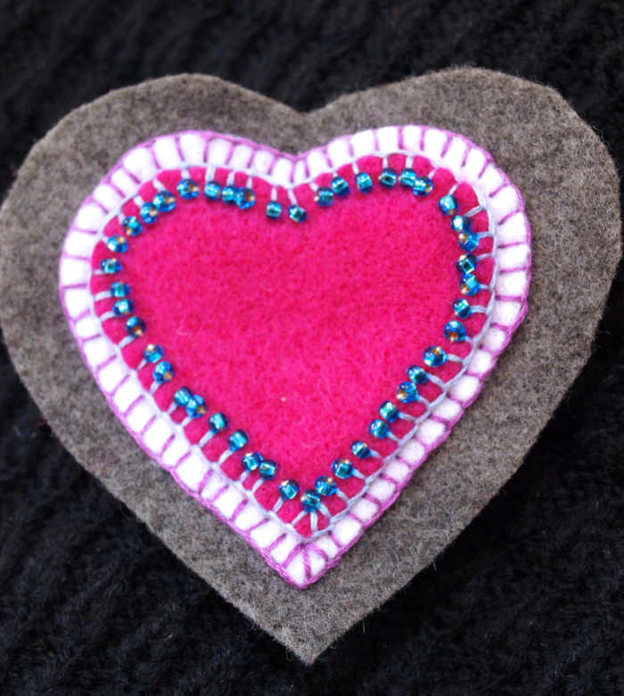 Heart shaped felt brooch. I used a blanket stitch for all the layers and added the blue beads after I had stitched the pink heart to the white heart.