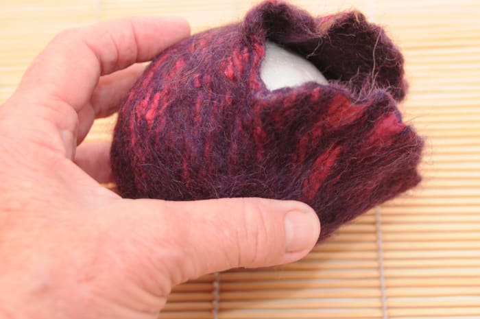 A fully fulled purse with the small polystyrene ball placed inside. This purse was nuno felted with silk on the decorative layer.