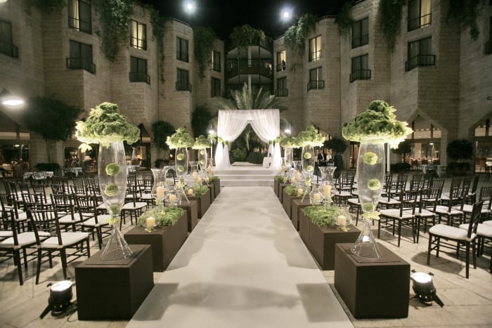 Artificial mixed with real plants and flowers make for a unique and classy setting. The picture above has tall glass vases topped with artificial moss and cymbidium orchids. Add some up lighting beneath each one and you have a dramatic look.