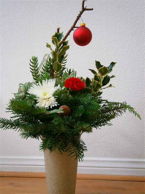This centerpiece uses recycled ribbon, ornament and free pine cones and Christmas greens. The cost is taken up by the vase and floral foam.