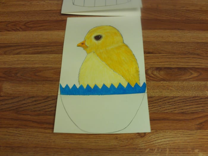 Here I have added the deep brown eyes to the chicken, and shaded in the top of his blue egg.