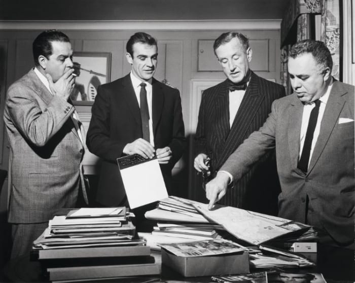 During the filming preparation of "Dr. No," Cubby Broccoli, Sean Connery, Ian Flemming, and Harry Saltzman look at a map of Jamaica.